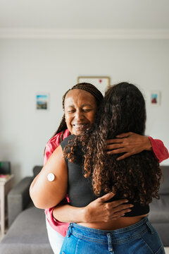 African mother hugging her daughter with diabetes patch - Family lifestyle and people diseases concept - Focus on mother face - Vertical photo
