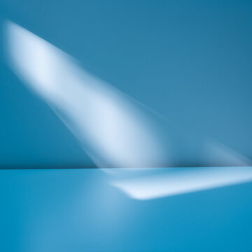 Blue background with blurred light and shadows on wall. Winter background for product presentation.