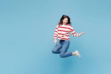 Obraz premium Full body young happy singer woman she wear red striped sweatshirt casual clothes jump high play imaginary air guitar isolated on plain pastel light blue background studio portrait. Lifestyle concept.