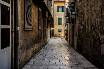 Quiet narrow street in the old town of Zadar with a bicycle parked near colorful historic buildings. Mediterranean city atmosphere, urban travel scene and coastal lifestyle in Croatia.
