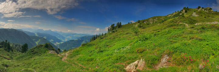 Panoramic view of lush green hills and mountains under a bright sky