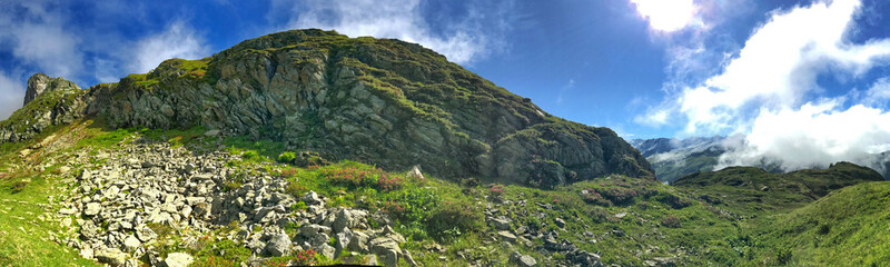 Panoramic view of lush greenery and rocky terrain under a bright blue sky