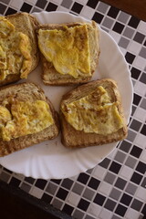 Torradas com ovos no caf&eacute; da manh&atilde;, prato branco sobre a mesa com comida refor&ccedil;ada de desjejum