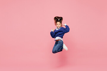 Full body little child kid girl 8-9 years old she wear blue shirt have fun jump high do winner gesture look camera isolated on pink color background studio. Mother's Day love family lifestyle concept