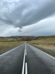 Asphalt road wet after rain goes into the distance, a part of the Chuisky tract, Altai, Russia