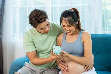 Asian couple embracing parenthood and saving for their future with a piggy bank at home