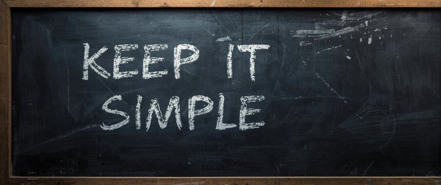 A well known saying for business strategy, project management, and planning: Keep It Simple written in chalk on a used blackboard