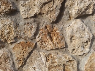 Fototapeta premium Rough natural stone wall texture with warm earthy tones