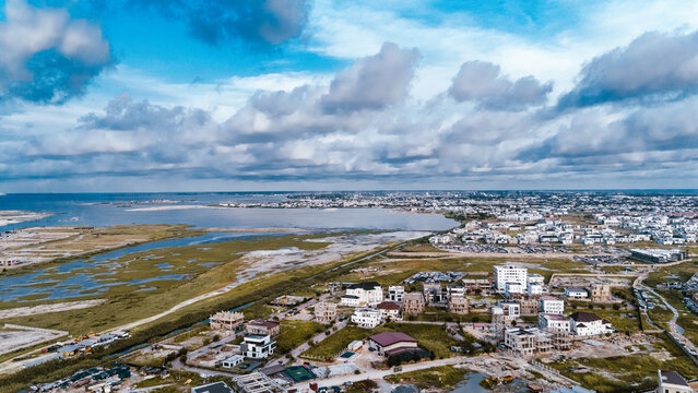 Aerial view of the tranquil lagoon mirroring the expansive sky, juxtaposed against the developing urban landscape of Lekki, Lagos, Nigeria.