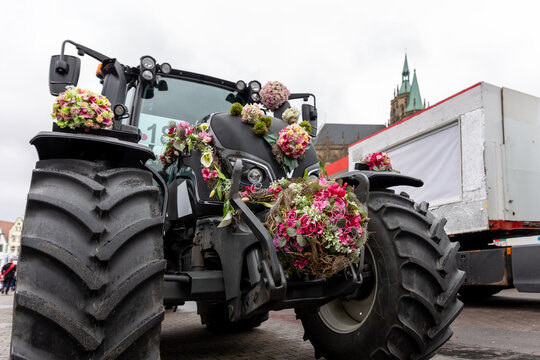 Decorated tractor colorful floral arrangements during Fasching carnival parade Erfurt city center. Festive agriculture machinery historic architecture highlights German tradition culture celebration