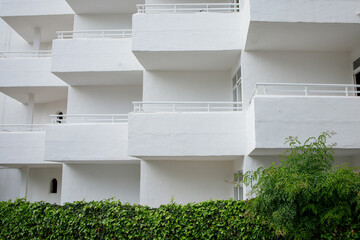 White minimalistic hotel building exterior with symmetrical balconies on Mallorca island in Spain. Architectural style of Cala D'Or town.