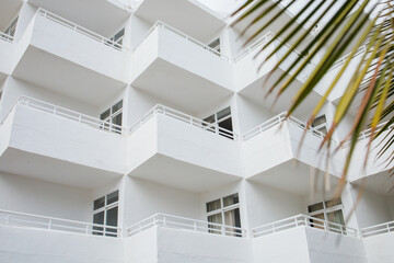White minimalistic hotel building exterior with symmetrical balconies on Mallorca island in Spain. Architectural style of Cala D'Or town.