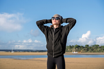 sporty woman with hands on head after running on the beach