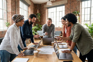 A diverse group of colleagues collaborating around a wooden conference table in a modern office