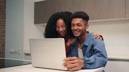 A joyful couple sharing a delightful experience while using a laptop together at home, engaged in laughter and connection during their leisure time, creating memorable moments together.