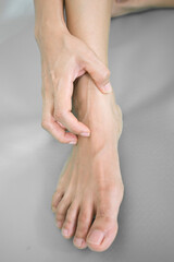 Fototapeta premium Close-up of female hands massaging her feet on grey background