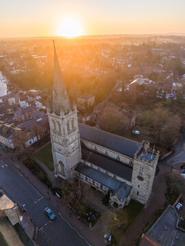 Aerial view of the golden sunrise casting a warm glow over the historic Rugby Parish Church and the surrounding town, Rugby, England, United Kingdom.