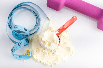 Fitness and nutrition essentials: protein powder, measuring tape, and dumbbell for healthy lifestyle