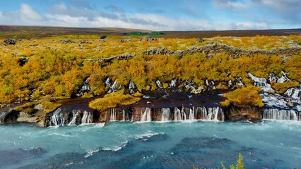 view of stunning Hraunfossar waterfalls in Iceland during summer. Turquoise glacial water cascades over ancient lava fields creating a unique natural wonder © Rajesh
