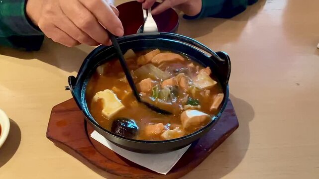 Salmon belly with spicy miso soup served in black bowl
