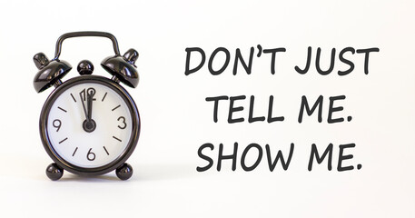 Tell or show symbol. Concept words Do not just tell me, show me on beautiful white paper. Beautiful white paper background. Black alarm clock. Business tell or show concept. Copy space.