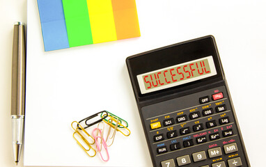 Successful symbol. Concept word Successful on beautiful black calculator's screen. Beautiful white background. Colored paper and black pen. Business successful concept. Copy space.