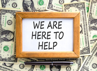 Support, help and we are here to help symbol. Concept words We are here to help on beautiful wooden picture frame. Beautiful dollar bills background. Business we are here to help concept. Copy space.