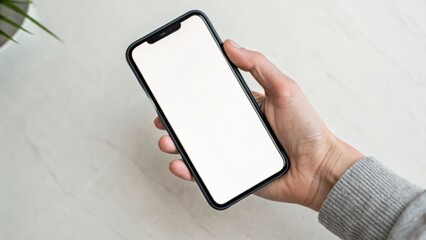 A hand holding a modern smartphone with a blank screen against a minimalistic background.