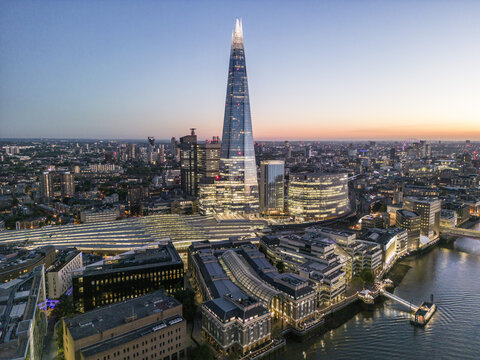 Aerial view of the iconic Shard piercing the skyline, standing tall amidst the tapestry of buildings and the winding Thames, London, United Kingdom.