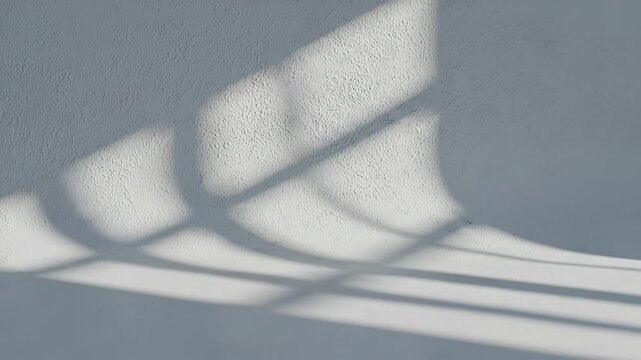 Abstract minimalist background featuring window light and shadow patterns on a curved wall.