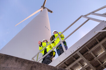 Workers inspect wind turbine at construction site during bright day with clear blue sky © Freeday photo