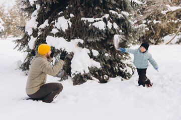 Father and son enjoying winter playing snowball fight in snow covered park, having fun outdoors with family