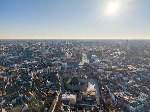 Aerial view of the Gravensteen castle surrounded by canals, ancient rooftops basking in the winter sun, Ghent, Flanders, Belgium.