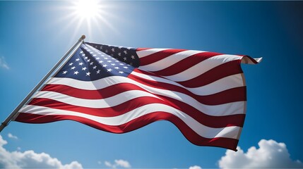Obraz premium American flag waving in the wind against a clear blue sky with white clouds and sun shining brightly