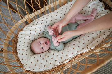 A portrait of a newborn baby in a crib. The baby is smiling and playing.