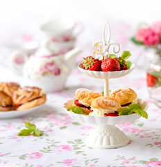 Cream puffs cakes or profiterole filled with whipped cream served with strawberries