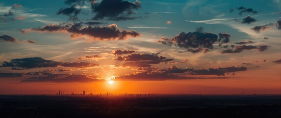 Fototapeta premium As dawn breaks, the city skyline appears as a silhouette against the colorful shades of orange and blue, symbolizing a peaceful start to a new day filled with promise