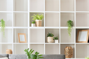 Modern Minimalist Living Room Interior Design Featuring a White Square-Spaced Bookshelf, Grey Sofa, and Plants, Neatly Organized for a Homey Ambience, Illuminated by Natural Light. © Jesus