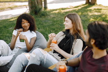 Three friends talking while sitting on the bean bag chairs in a park