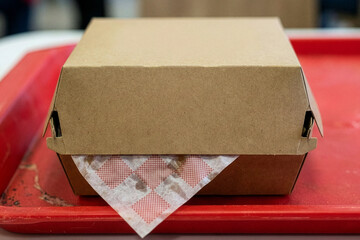 Closed kraft burger box mockup on red fast food tray