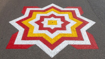 Geometric painted star design in concentric red yellow and white lines on asphalt surface