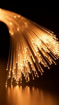 Close Up of Fiber Optic Cables Emitting Golden Light on a Dark Background.