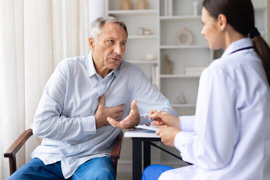 Senior male patient describing chest discomfort to female doctor during medical consultation, highlighting heart health and cardiovascular concerns