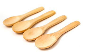 Four wooden spoons arranged on a white background, natural material kitchen utensils