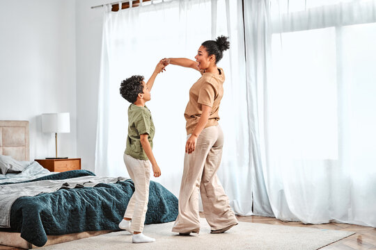 Mother and son joyfully dancing at home, having fun and sharing happy moments together in a cozy interior.