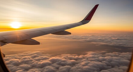 Obraz premium Airplane Wing View During a Vibrant Golden Hour Sunset over Fluffy Clouds, Seen from a Passenger Window at High Altitude, Capturing the Serene Beauty of Air Travel