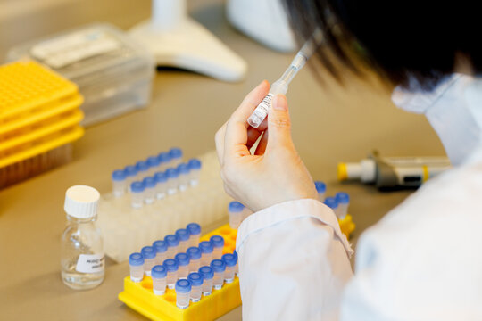 The hand of a chemist working in a lab, filling test tubes with an unknown liquid.