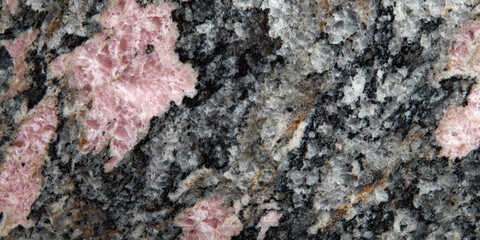 Macro detail of pink and black granite rock, natural stone texture background. mineral surface pattern shows crystalline material for geology or abstract design elements