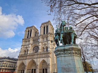 Paris, France - December 10, 2025: Low-angle view of the Notre-Dame Cathedral in Paris and the bronze Charlemagne and his Guards statue stands prominently against the iconic twin towers