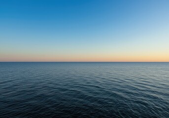 Obraz premium A beautiful wide open view of the expansive horizon line separating the clear blue sky above and the calm water below at sunset time ,wide ,sunrise ,sky